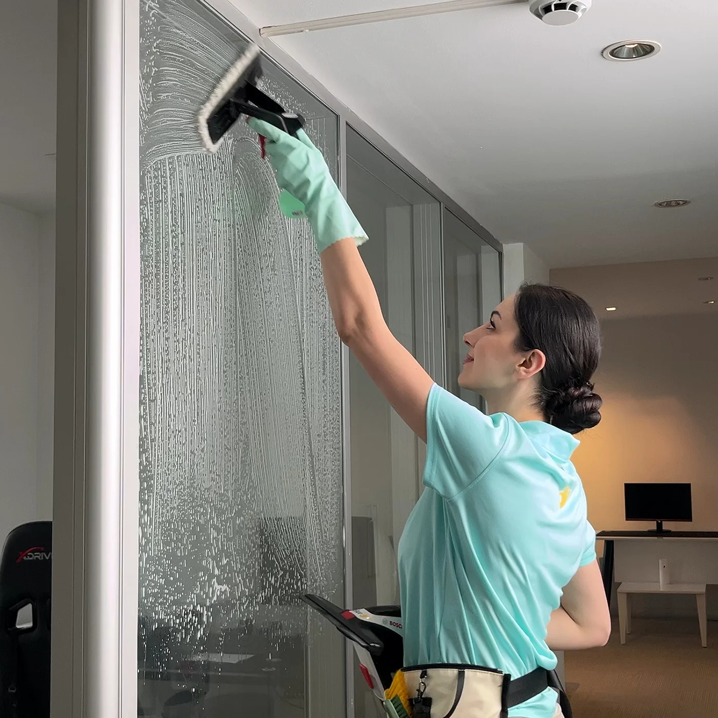 Ofis cam temizliğinde cam temizleyici deterjan ile yüzeydeki kir tabakası gevşetiliyor