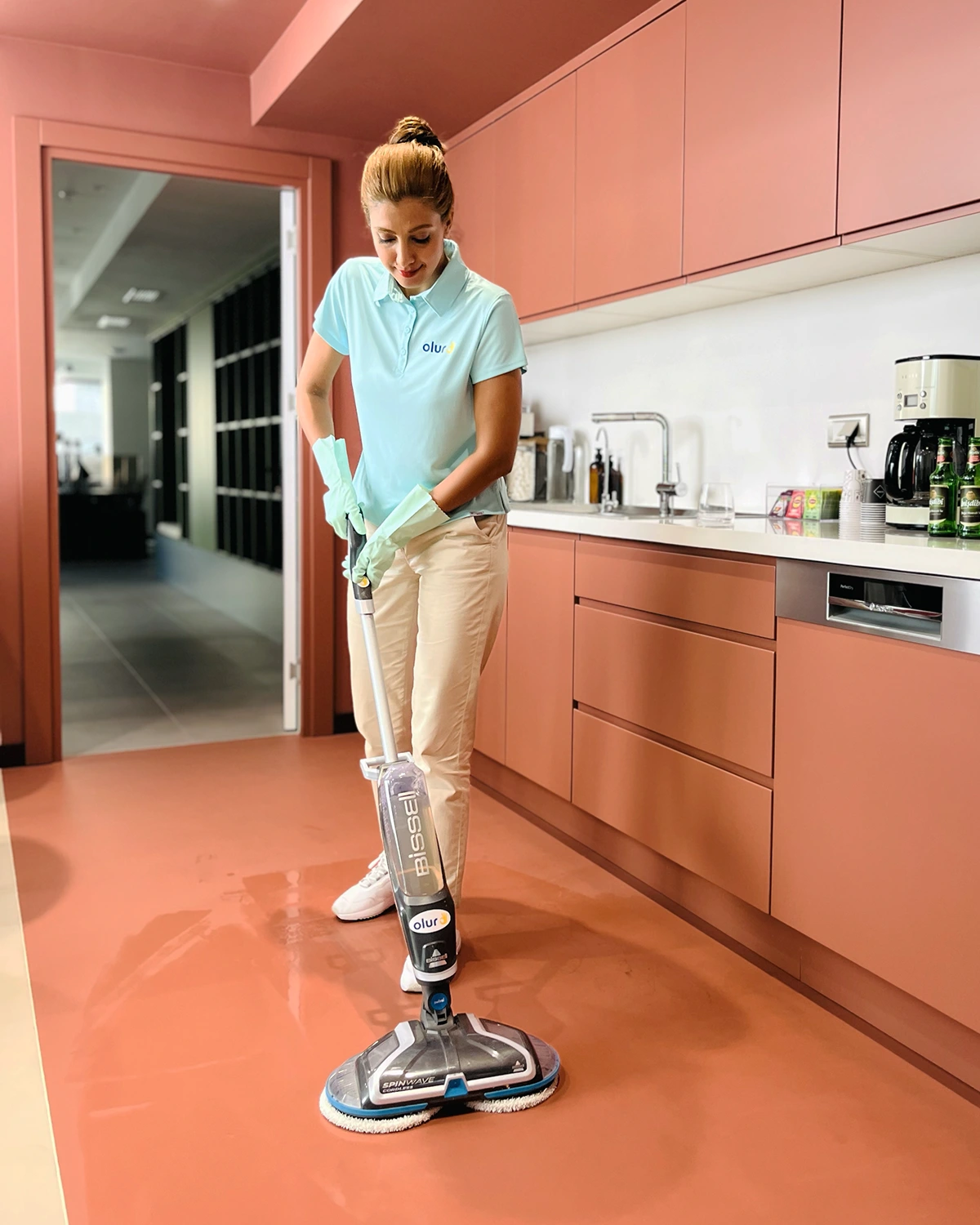 Temizlikçi, ofis mutfak zeminini kablosuz zemin silme makinesiyle temizliyor